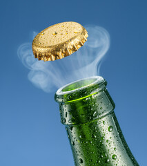 Canvas Print - Opening beer bottle on blue background. Gas cloud going out of the beer bottle blowing the cap.