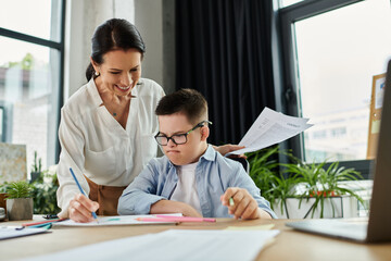 A mother helps her son with Down syndrome with his homework in their home office.