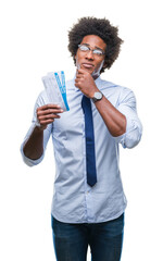 Sticker - Afro american man holding boarding pass over isolated background serious face thinking about question, very confused idea