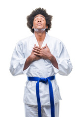 Canvas Print - Afro american man wearing karate kimono over isolated background smiling with hands on chest with closed eyes and grateful gesture on face. Health concept.