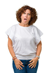 Canvas Print - Beautiful middle ager senior woman wearing white t-shirt over isolated background In shock face, looking skeptical and sarcastic, surprised with open mouth