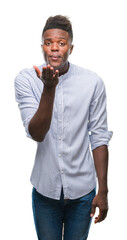 Canvas Print - Young african american man over isolated background looking at the camera blowing a kiss with hand on air being lovely and sexy. Love expression.