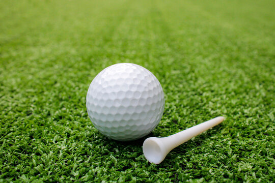 Golf balls and tees are placed on artificial grass.