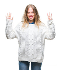 Wall Mural - Beautiful young blonde woman wearing winter sweater over isolated background showing and pointing up with fingers number eight while smiling confident and happy.