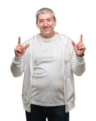 Sticker - Handsome senior man wearing sport clothes over isolated background amazed and surprised looking up and pointing with fingers and raised arms.