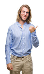 Poster - Young handsome man with long hair wearing glasses over isolated background smiling with happy face looking and pointing to the side with thumb up.