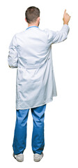 Sticker - Handsome doctor man wearing medical uniform over isolated background Posing backwards pointing behind with finger hand