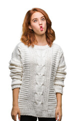 Sticker - Young beautiful woman over isolated background wearing winter sweater making fish face with lips, crazy and comical gesture. Funny expression.