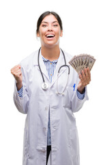 Canvas Print - Young hispanic doctor woman holding dollars screaming proud and celebrating victory and success very excited, cheering emotion