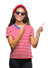 Wall Mural - Young beautiful arab woman wearing sunglasses over isolated background smiling and looking at the camera pointing with two hands and fingers to the side.