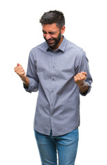 Canvas Print - Adult hispanic man over isolated background very happy and excited doing winner gesture with arms raised, smiling and screaming for success. Celebration concept.