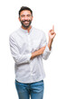 © Krakenimages.com - Adult hispanic man over isolated background with a big smile on face, pointing with hand and finger to the side looking at the camera.
