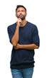 © Krakenimages.com - Adult hispanic man over isolated background with hand on chin thinking about question, pensive expression. Smiling with thoughtful face. Doubt concept.