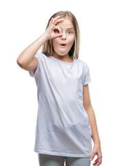 Young beautiful girl over isolated background doing ok gesture shocked with surprised face, eye looking through fingers. Unbelieving expression.