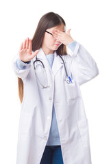 Poster - Young Chinese doctor woman over isolated background covering eyes with hands and doing stop gesture with sad and fear expression. Embarrassed and negative concept.