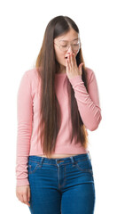 Wall Mural - Young Chinese woman over isolated background wearing glasses bored yawning tired covering mouth with hand. Restless and sleepiness.