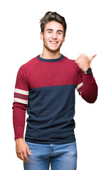 Young handsome man over isolated background smiling with happy face looking and pointing to the side with thumb up.