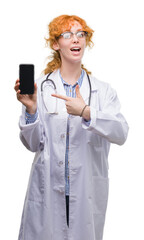 Canvas Print - Young redhead doctor woman showing smartphone very happy pointing with hand and finger