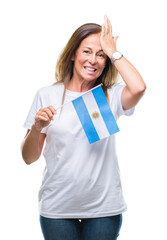 Sticker - Middle age hispanic woman holding flag of Argentina over isolated background stressed with hand on head, shocked with shame and surprise face, angry and frustrated. Fear and upset for mistake.