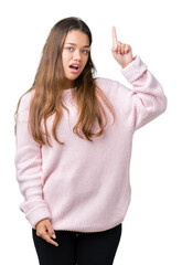 Wall Mural - Young beautiful brunette woman wearing pink winter sweater over isolated background pointing finger up with successful idea. Exited and happy. Number one.