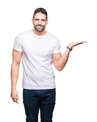 Young man wearing casual white t-shirt over isolated background smiling cheerful presenting and pointing with palm of hand looking at the camera.