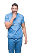 © Krakenimages.com - Handsome young doctor surgeon man over isolated background looking confident at the camera with smile with crossed arms and hand raised on chin. Thinking positive.