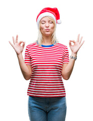 Sticker - Young beautiful blonde woman wearing christmas hat over isolated background relax and smiling with eyes closed doing meditation gesture with fingers. Yoga concept.