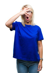 Canvas Print - Young beautiful blonde woman wearing glasses over isolated background peeking in shock covering face and eyes with hand, looking through fingers with embarrassed expression.