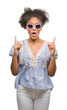 © Krakenimages.com - Young afro american woman wearing glasses over isolated background amazed and surprised looking up and pointing with fingers and raised arms.