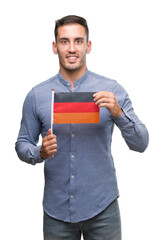 Canvas Print - Handsome young man holding a flag of Germany with a happy face standing and smiling with a confident smile showing teeth