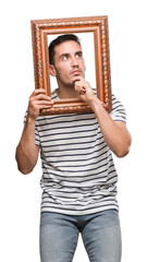 Sticker - Handsome young man looking through vintage art frame serious face thinking about question, very confused idea