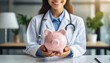 © Your Hand Please - woman doctor holding a piggy bank, symbolizing financial support and donations to healthcare and medical facilities