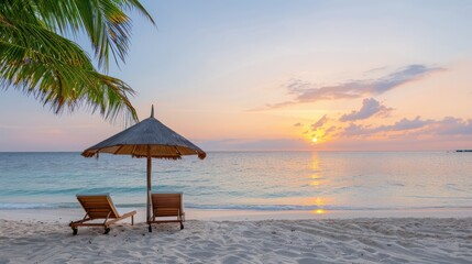 Poster - A beach with two lounge chairs under a beach umbrella. The sky is blue and the sun is setting