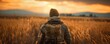 © Pavel Kachanau - A man walks through a field of tall grass with the sun setting in the background