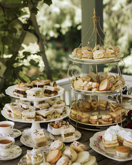 Wall Mural - A charming display of tea sandwiches, scones, and assorted teas arranged on vintage china at a garden tea party