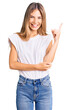 © Krakenimages.com - Beautiful caucasian woman with blonde hair wearing casual white tshirt with a big smile on face, pointing with hand and finger to the side looking at the camera.