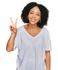 Poster - Young african american girl wearing casual clothes showing and pointing up with fingers number two while smiling confident and happy.