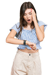 Wall Mural - Young beautiful caucasian girl wearing casual clothes looking at the watch time worried, afraid of getting late