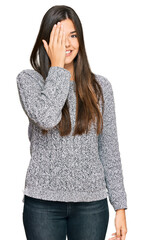 Canvas Print - Young brunette woman wearing casual winter sweater covering one eye with hand, confident smile on face and surprise emotion.