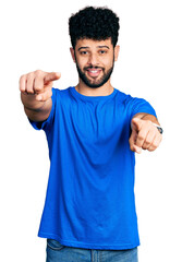 Wall Mural - Young arab man with beard wearing casual blue t shirt pointing to you and the camera with fingers, smiling positive and cheerful