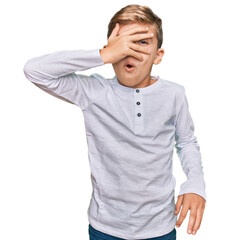 Little caucasian boy kid wearing casual clothes peeking in shock covering face and eyes with hand, looking through fingers with embarrassed expression.