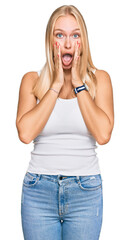 Wall Mural - Young blonde girl wearing casual style with sleeveless shirt afraid and shocked, surprise and amazed expression with hands on face