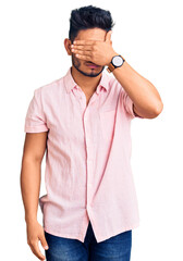 Wall Mural - Handsome latin american young man wearing casual summer shirt covering eyes with hand, looking serious and sad. sightless, hiding and rejection concept