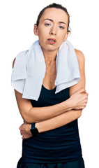 Poster - Young caucasian woman wearing sportswear and towel shaking and freezing for winter cold with sad and shock expression on face