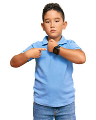 Canvas Print - Little boy hispanic kid wearing casual clothes in hurry pointing to watch time, impatience, looking at the camera with relaxed expression