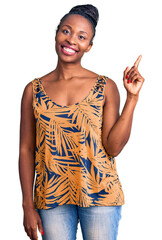 Canvas Print - Young african american woman wearing casual clothes pointing finger up with successful idea. exited and happy. number one.