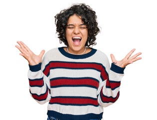 Canvas Print - Young hispanic woman with curly hair wearing casual clothes celebrating mad and crazy for success with arms raised and closed eyes screaming excited. winner concept