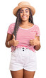© Krakenimages.com - Young african american woman with braids wearing summer hat success sign doing positive gesture with hand, thumbs up smiling and happy. cheerful expression and winner gesture.