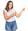 © Krakenimages.com - Young caucasian woman wearing casual white tshirt smiling and looking at the camera pointing with two hands and fingers to the side.