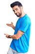 © Krakenimages.com - Young handsome man with beard wearing casual t-shirt inviting to enter smiling natural with open hand